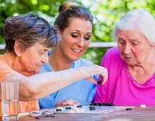 Deux femmes âgées et une femme plus jeune réunies autour d’un jeu de société.