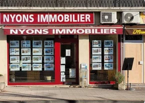 La façade rouge de l’agence Nyons Immobilier sur la place de la Libération