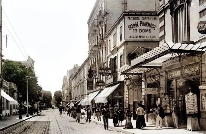 Rue de la République à Avignon autrefois : rails du tramway, passants, Grande Pharmacie des Doms et marquise de verre au-dessus du trottoir.