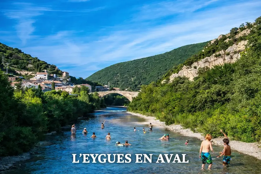 Baigneurs dans l’Eygues en aval de Nyons, entre une plage de galets et des collines boisées.