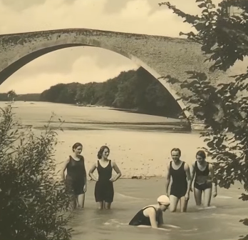 Photographie sépia de cinq personnes en maillot dans l’Eygues, avec l’arche du Pont Roman de Nyons en arrière-plan.