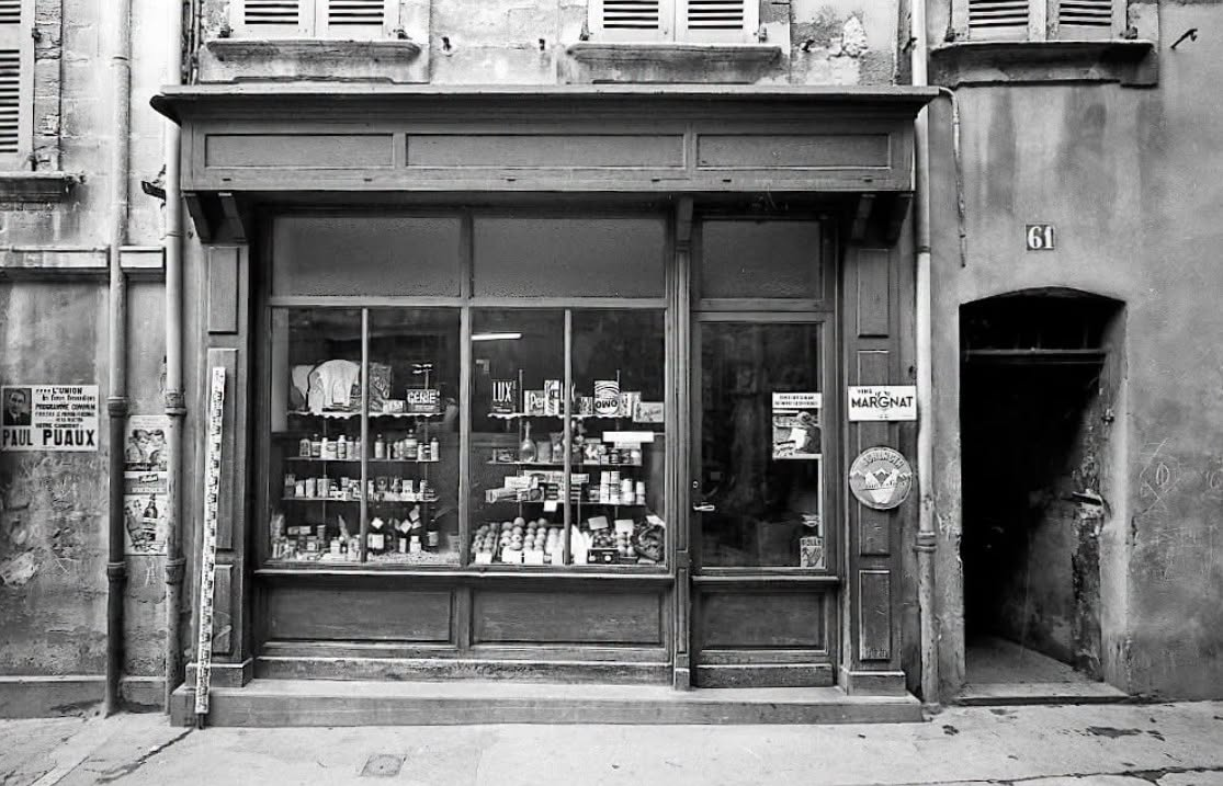 Ancienne épicerie du quartier de la Balance à Avignon en 1964, avec vitrine en bois, produits alimentaires, publicités Lux, Omo et Margnat.