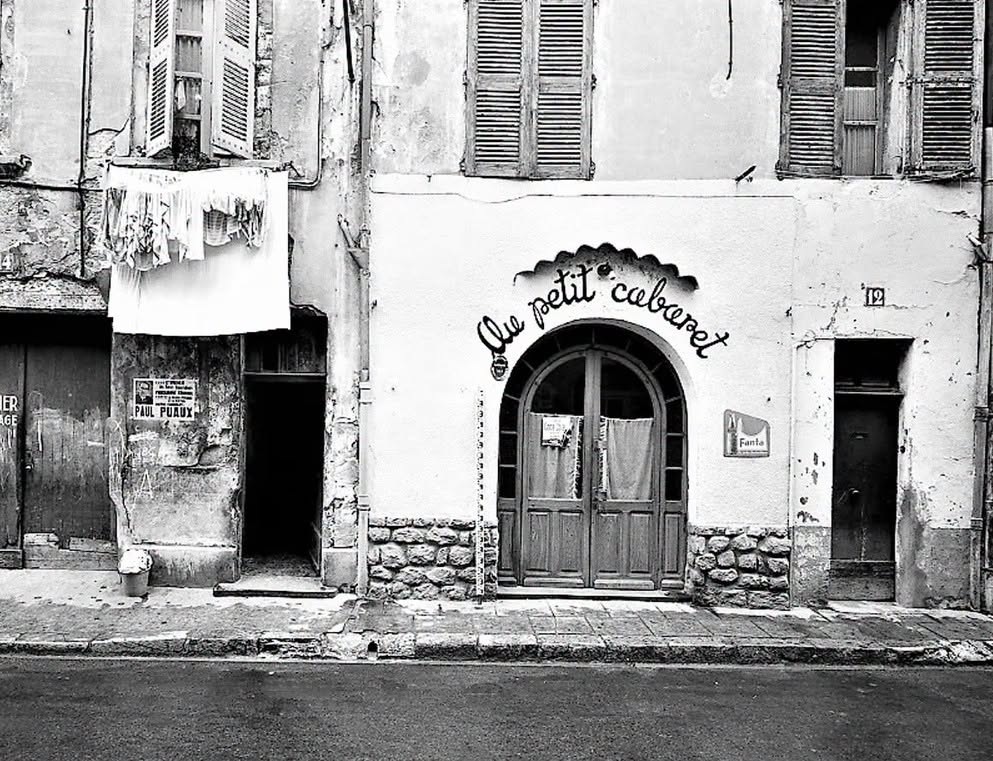 Ancienne façade du Petit Cabaret dans le quartier de la Balance à Avignon, photographiée en 1964, avec volets en bois, linge aux fenêtres et publicité Fanta.