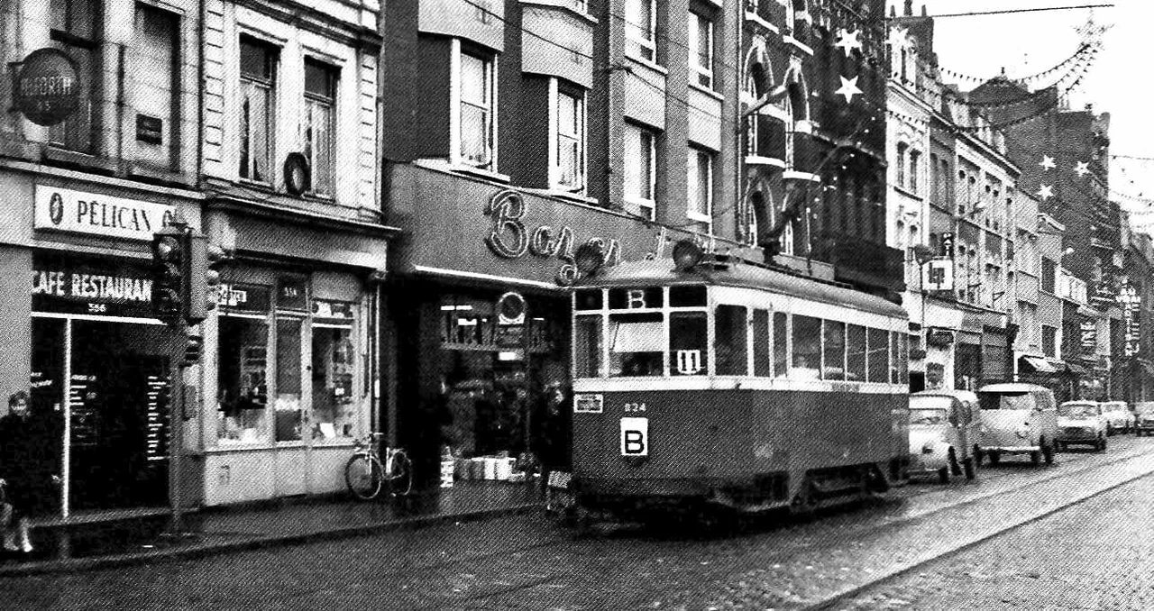 Ancienne photographie du Bazar de Wazemmes rue Léon-Gambetta à Lille, avec le tramway B, le café-restaurant Le Pélican, des voitures et des étoiles décoratives.