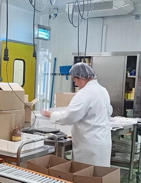 Personne en blouse et charlotte au poste de conditionnement de la Biscuiterie de Provence.