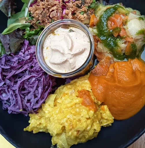Assiette colorée au Bistrotteur avec riz jaune, chou rouge, salade, légumes et sauce en verrine.