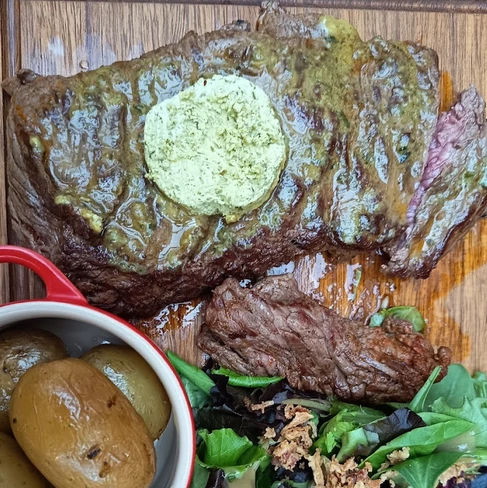 Pièce de viande grillée sur une planche au Bistrotteur, garniture aux herbes, pommes de terre et salade.