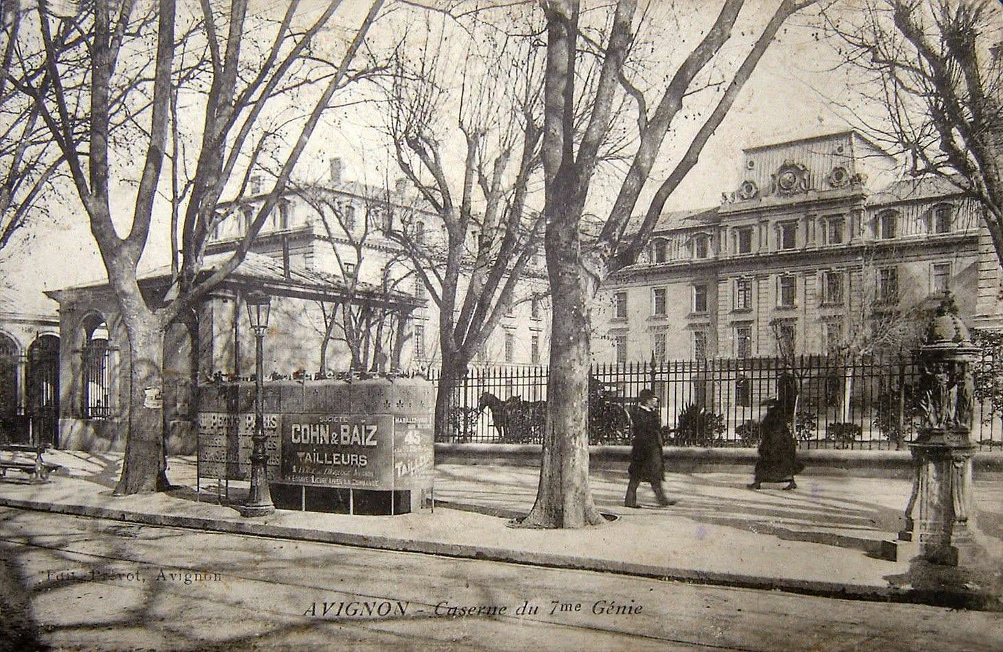 Caserne Hautpoul du 7e génie à Avignon au début du XXe siècle, avec platanes, chevaux, vespasienne publicitaire et fontaine.