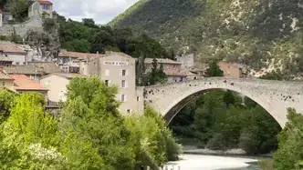 Le pont Roman enjambant l’Eygues à Nyons, avec les maisons et les collines en arrière-plan.