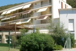 Façade claire avec balcons et végétation au premier plan.