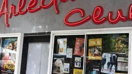 Entrée du cinéma L’Arlequin à Nyons, avec son enseigne rouge et ses affiches.