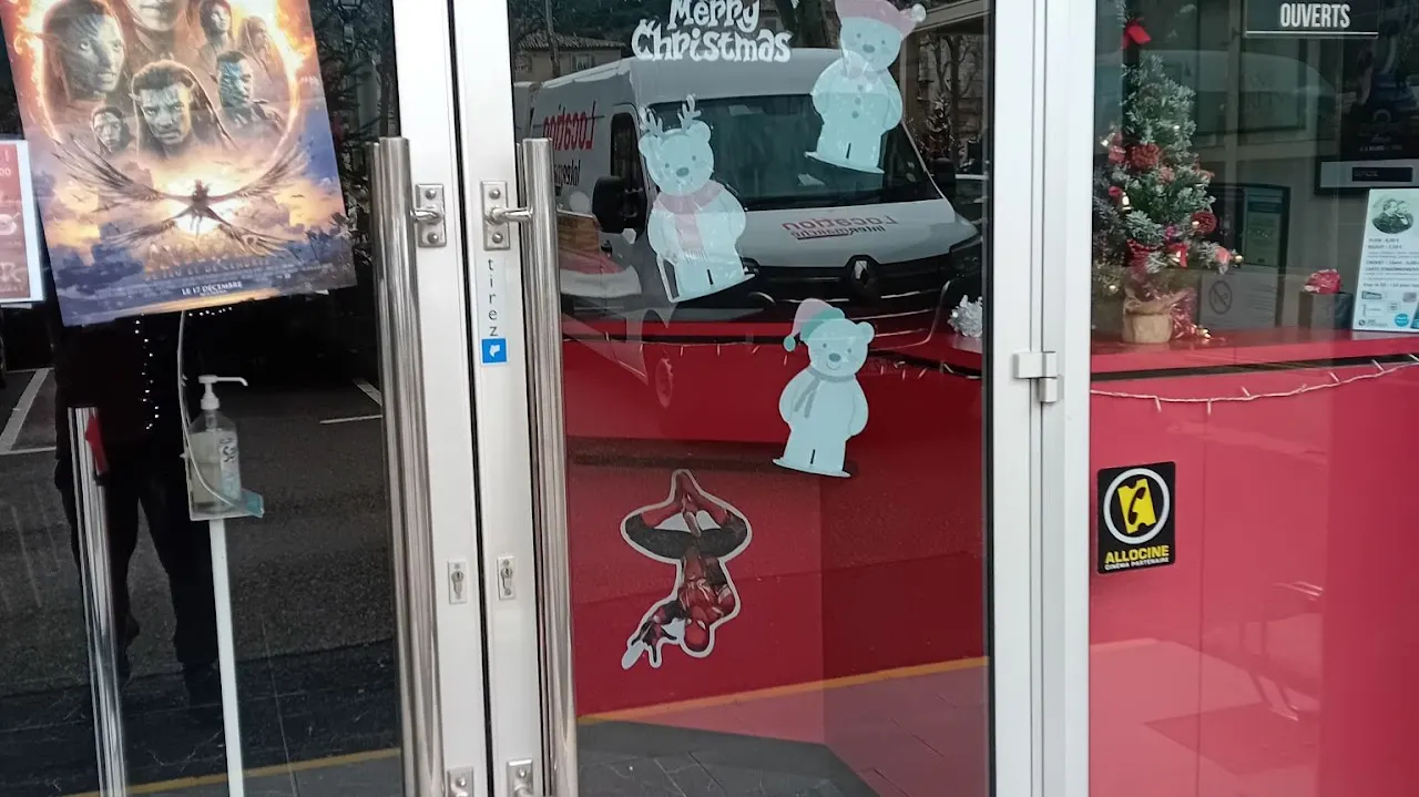 Portes vitrées et comptoir rouge à l’entrée du cinéma L’Arlequin à Nyons.