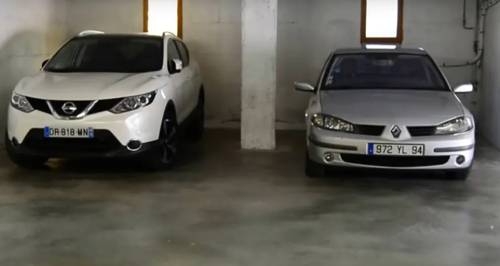 Deux voitures stationnées dans un garage couvert de la résidence.