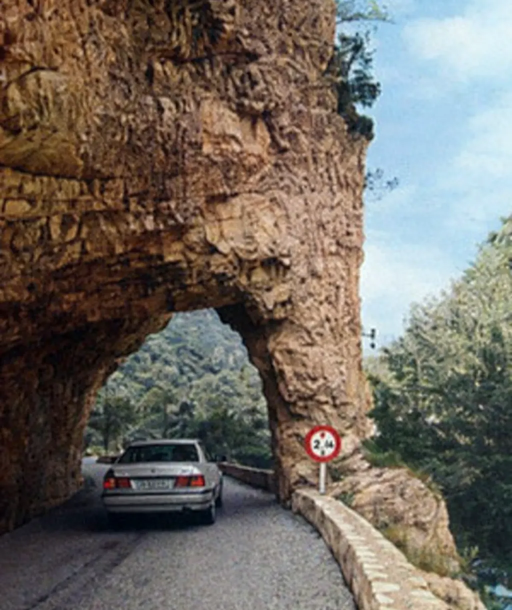Route étroite creusée dans la roche aux gorges de Trente-Pas, avec une voiture passant sous une arche naturelle près de Saint-Ferréol-Trente-Pas.