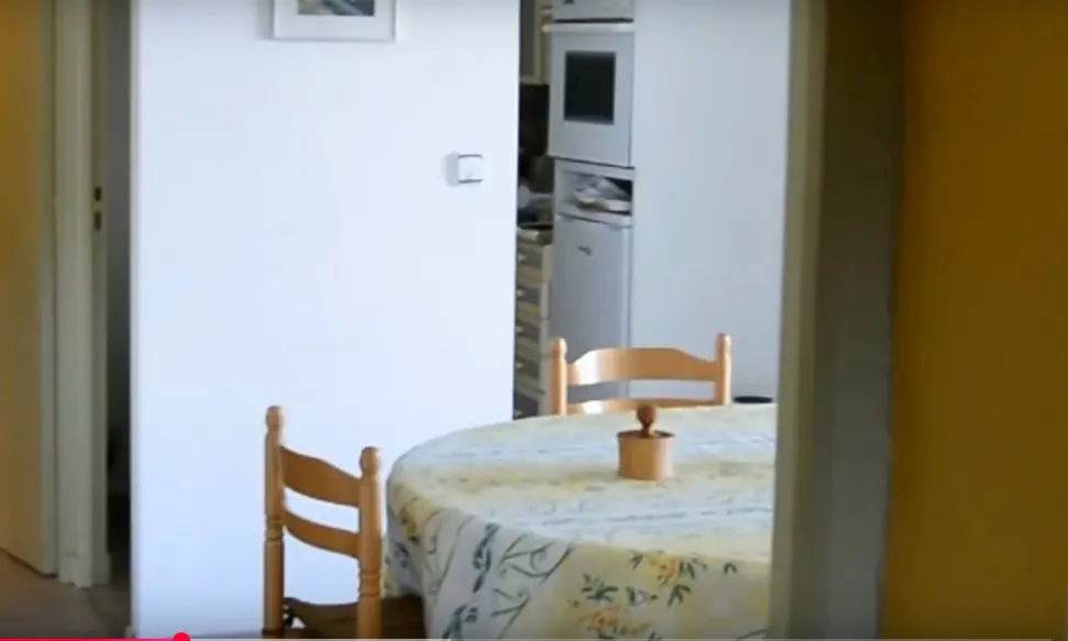 Table ronde et chaises dans un coin repas d’appartement, près d’une porte ouverte.