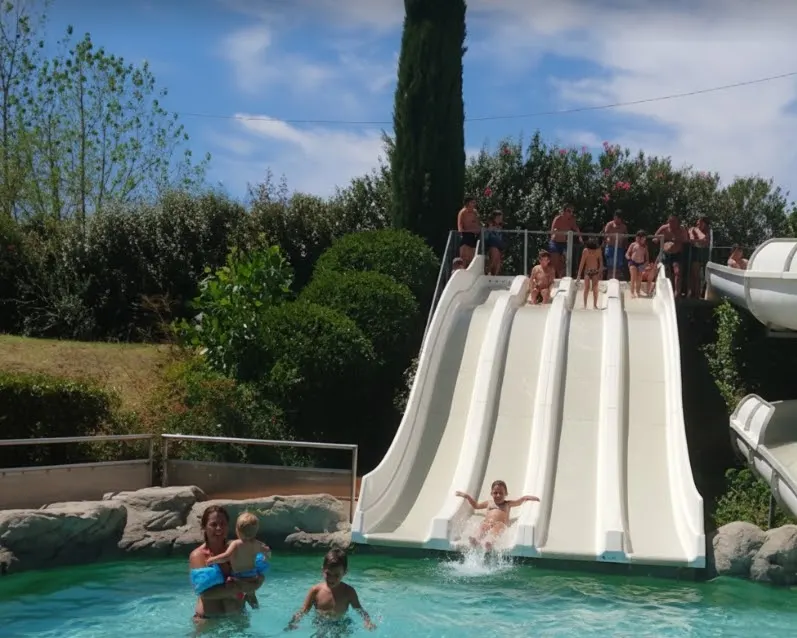 Toboggans du parc aquatique de Nyons avec enfants et familles se baignant et glissant dans les bassins en été, sous le soleil de la Drôme provençale.