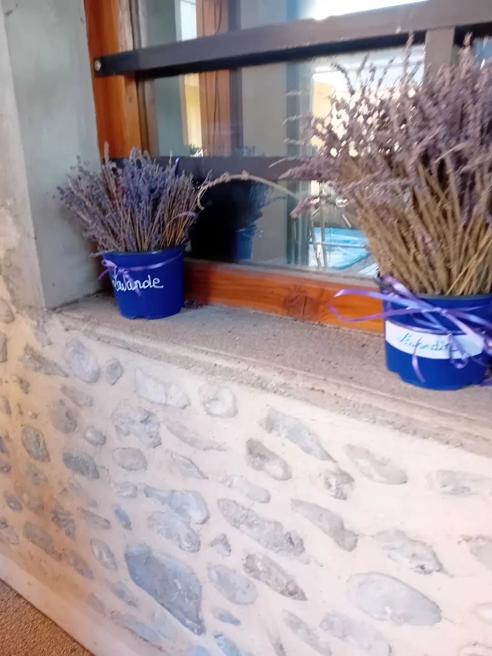 Bouquets de lavande séchée dans des pots bleus sur le rebord d’une fenêtre en pierre.