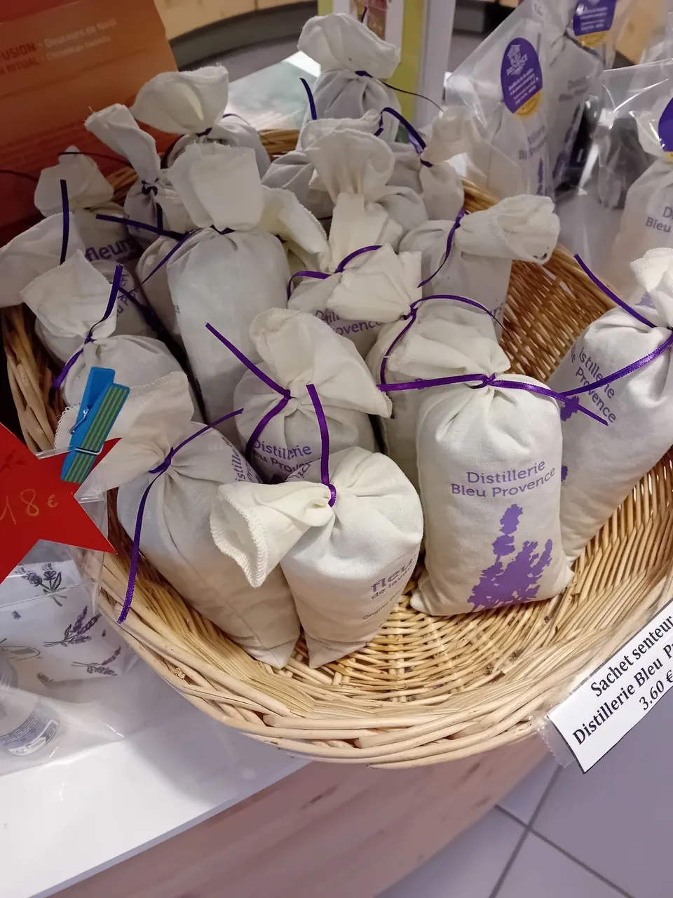 Sachets en tissu blanc portant le nom Distillerie Bleu Provence, présentés dans un panier.