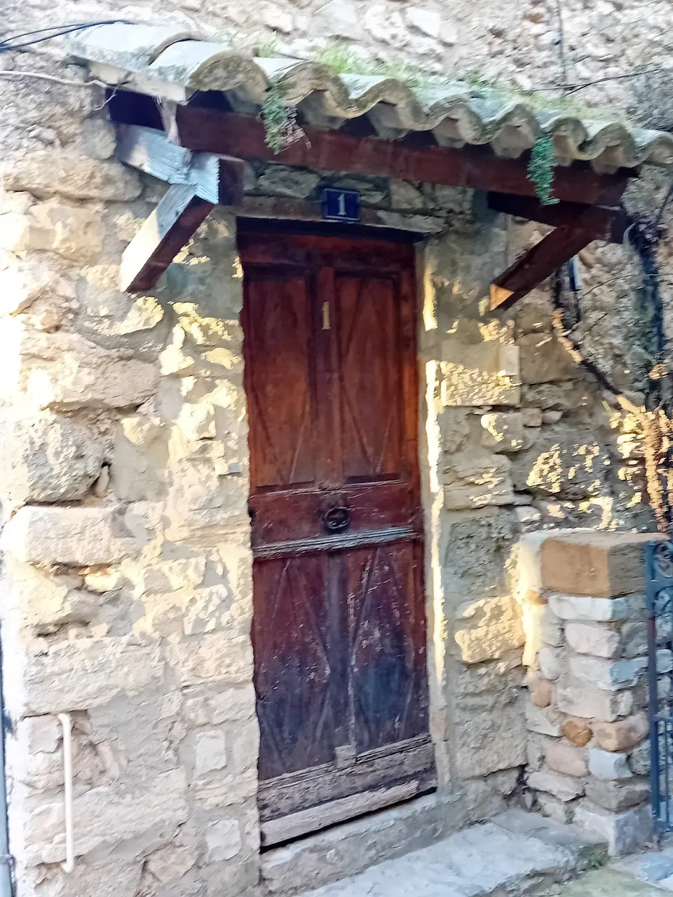 Vieille porte en bois sous un auvent en tuiles dans le centre ancien de Nyons