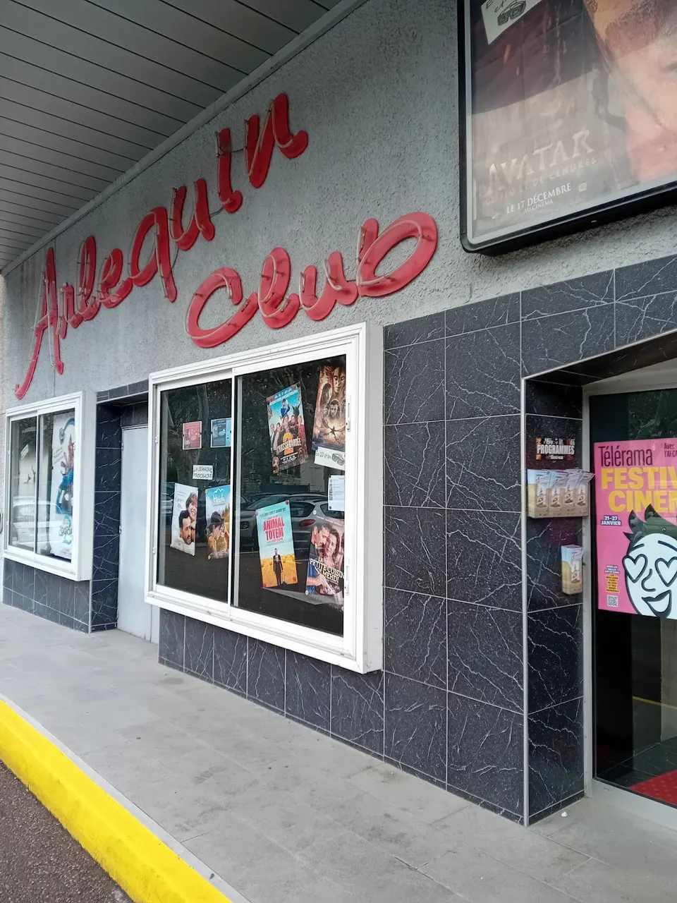 Enseigne rouge Arlequin Ciné et panneaux d’affiches sur la façade du cinéma à Nyons.