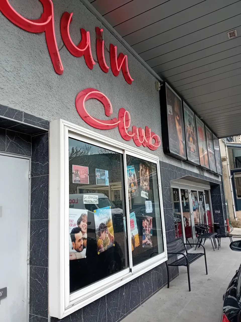 Vitrines d’affiches et bancs devant le cinéma L’Arlequin à Nyons.