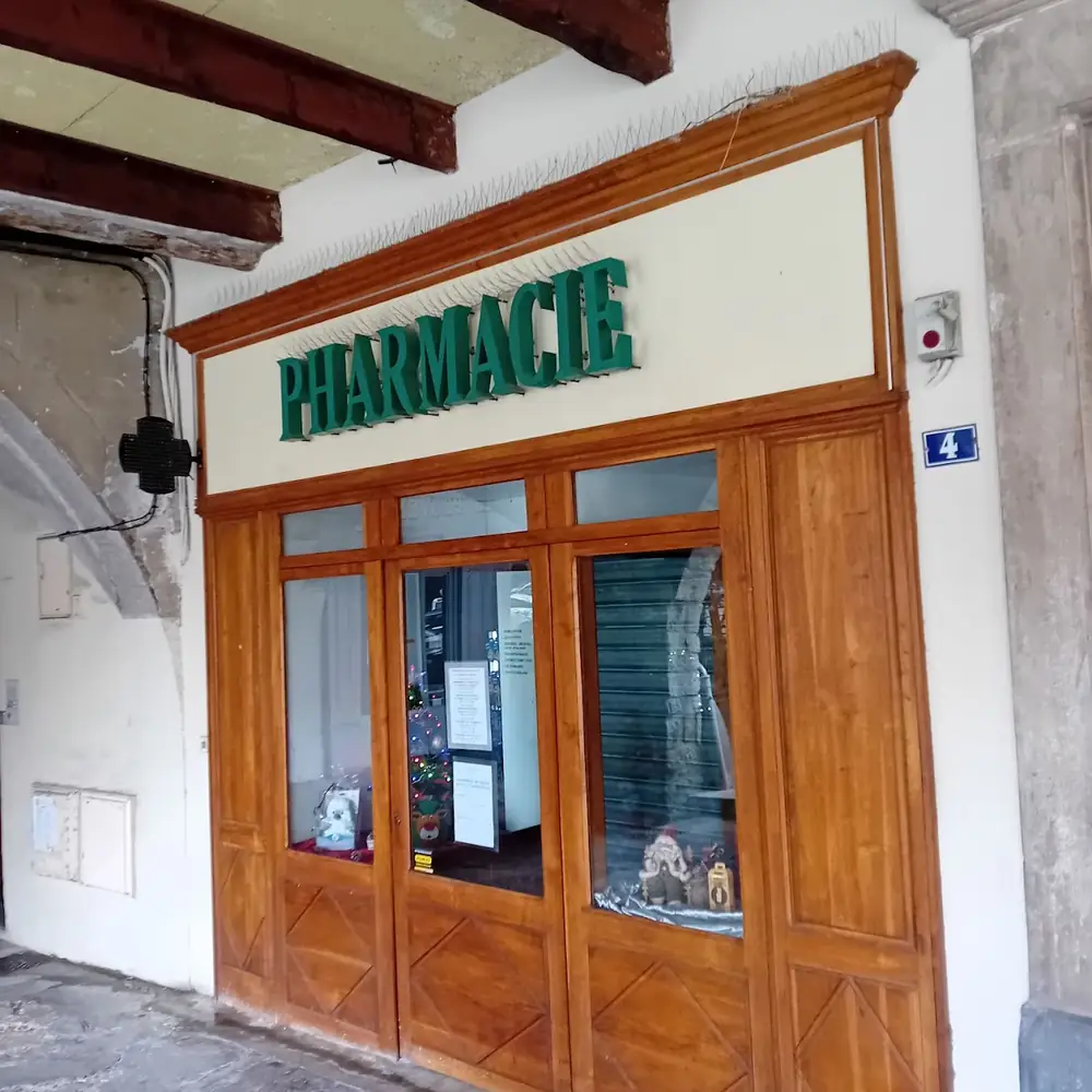 Ancienne façade de pharmacie à Nyons sous les arcades, avec devanture en bois et enseigne verte « Pharmacie »