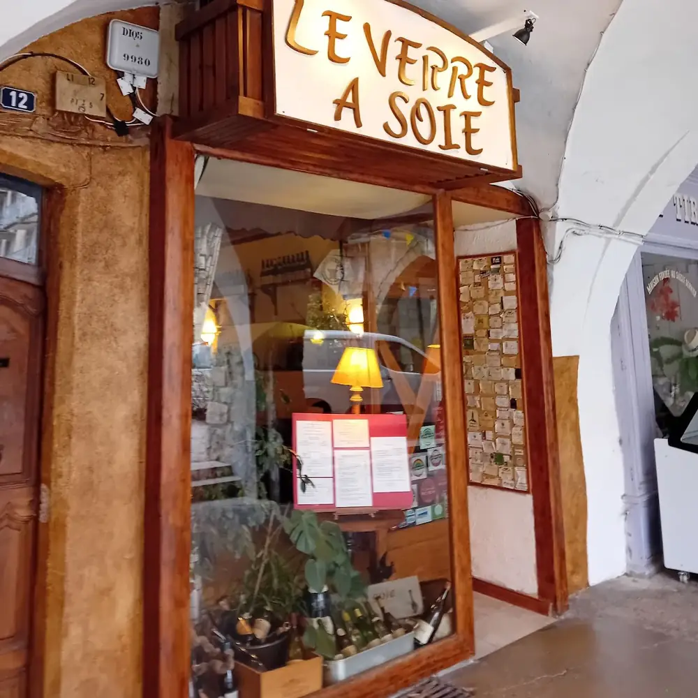 Devanture du restaurant « Le Verre à Soie » à Nyons, sous les arcades du centre historique, avec vitrine et enseigne lumineuse