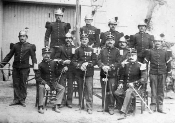 Pompiers de Nyons portant des casques et des sabres sur un ancien portrait de groupe.