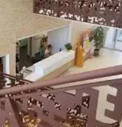 Comptoir d’accueil de l’hôpital de Nyons vu depuis l’étage, derrière un garde-corps ajouré.
