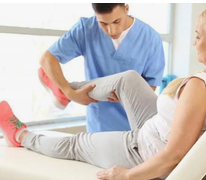 Un professionnel accompagne la mobilisation du genou d’une patiente assise sur une table de soins.