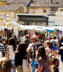 Des visiteurs parcourent les allées animées entre les stands et les parasols.