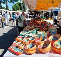 Des bols et de la vaisselle aux couleurs vives disposés sur une longue table de marché.
