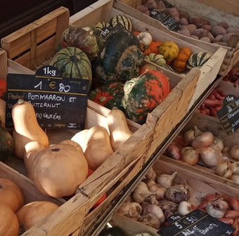 Étal de légumes de saison au marché de Valréas avec courges, oignons et produits frais.