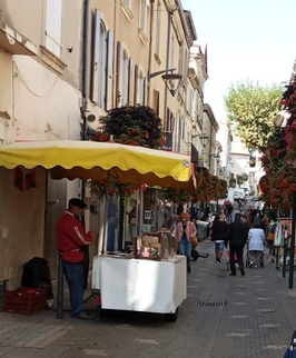 Marché de Valréas installé dans les rues du centre-ville avec commerçants et visiteurs.
