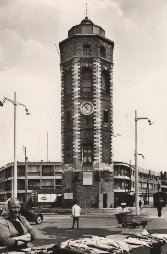 Photographie ancienne de la place du Minck à Dunkerque, avec une poissonnière, son étal de poissons, un chariot et la tour du Leughenaer.
