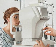 Patiente installée devant un appareil d’examen de la vue, le menton posé sur un support.
