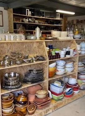 Vaisselle et ustensiles de cuisine d’occasion rangés sur des étagères.