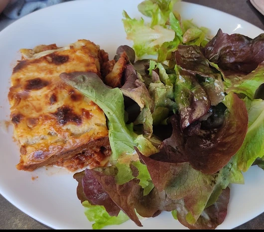 Part de lasagnes gratinées accompagnée d’une salade verte au Café de la Bourse à Nyons.