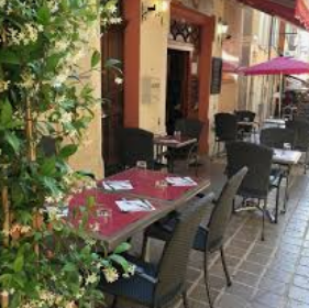 Tables et fauteuils sur la terrasse de Chem’s à Nyons, avec nappes rouges et végétation