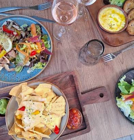Table de Lou Tex à Nyons avec plusieurs assiettes, salades et plats au fromage