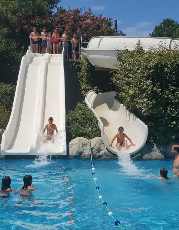 Baigneurs descendant les deux toboggans blancs de Nyonsoleïado dans un bassin.