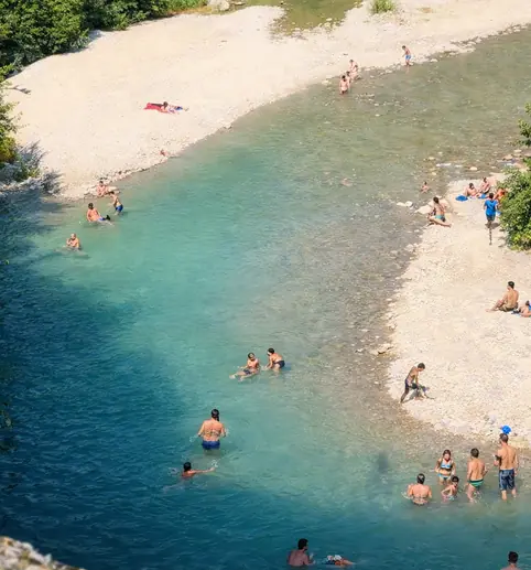 Vue plongeante sur les baigneurs et les rives de galets de l’Eygues à Nyons.