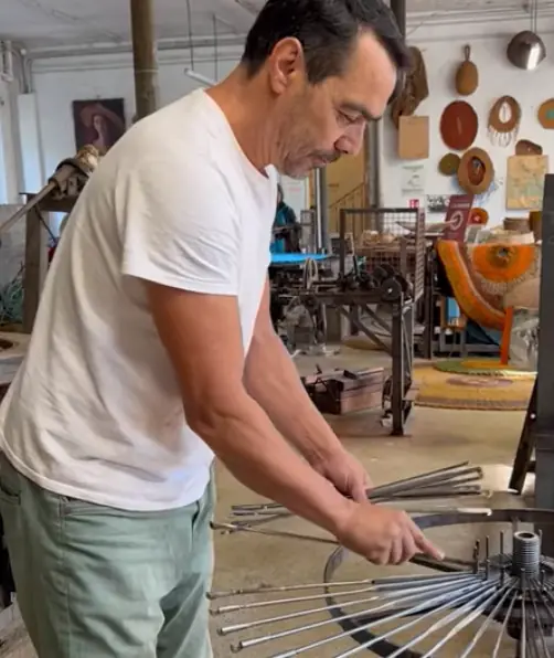 Artisan penché sur une machine de tissage à la Scourtinerie de Nyons.