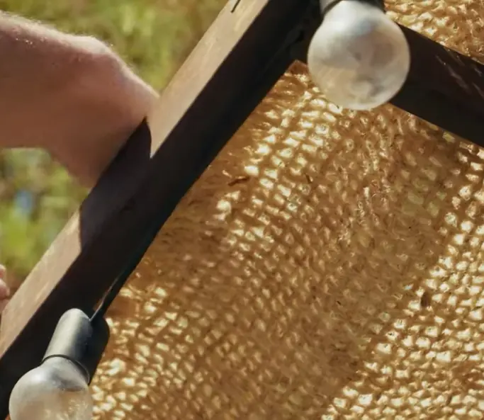 Main découpant une ombrière en fibre de coco avec des ciseaux.