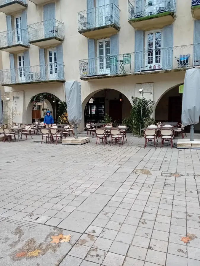 Façades et terrasses de cafés autour de la place des Arcades à Nyons.