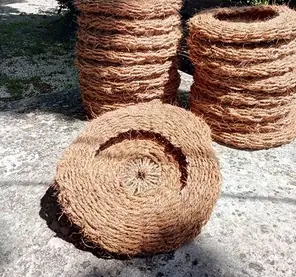 Piles de scourtins ronds bruns en fibre de coco à la Scourtinerie.