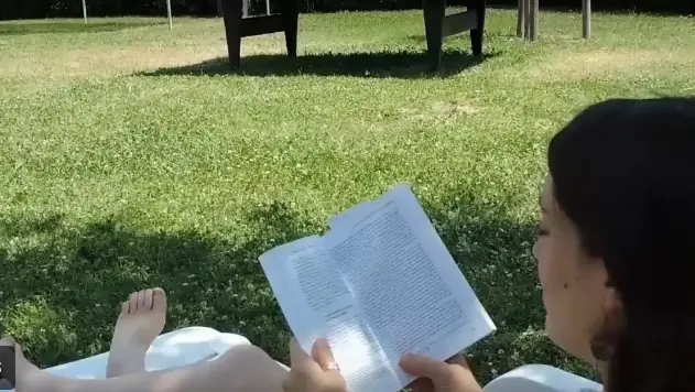 Lectrice installée sur la pelouse du parc aquatique Nyonsoleïado.
