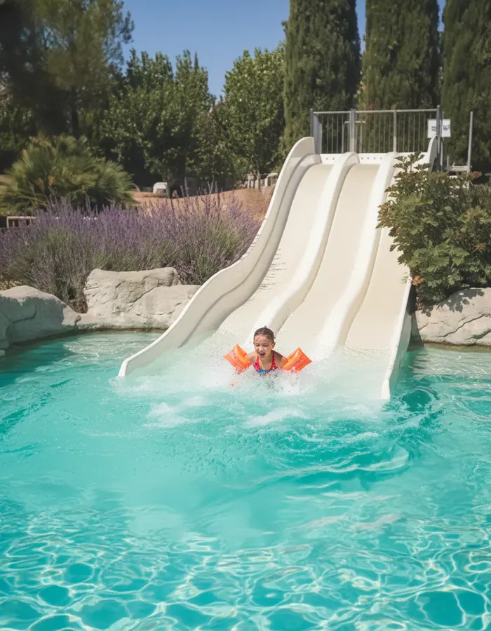 Baigneur arrivant dans l’eau au pied d’un toboggan blanc de Nyonsoleïado.