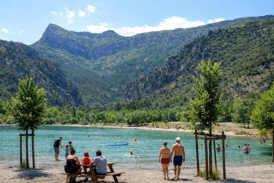 Familles au bord du lac du Pas des Ondes, avec une table de pique-nique et de jeunes arbres.