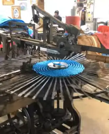 Scourtin bleu entouré de broches sur une machine de tissage à Nyons.